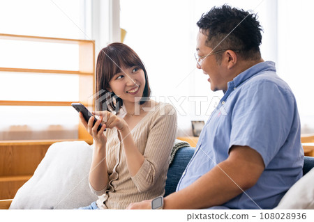 A man and a woman using smartphones in the living room A man and a woman using smartphones in the living room 108028936