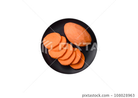 Fresh large pink sweet potato tubers with tomatoes and spices on a dark background 108028963