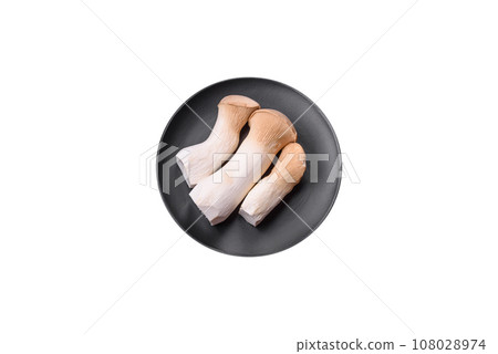 Pleurotus eryngii mushrooms on a dark concrete background 108028974