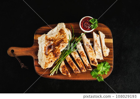Fast food.Chicken fillets fried until half cooked,product.Semi-finished chicken fillets,lightly fried,on a dark background with fresh herbs.Half-finished.Quick cooking at home.Quick cooking at home. 108029193