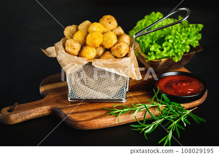 Fast food.Fast cooking.Chicken nuggets with salad.Chicken Breaded Raw Meat.Semifinished Breaded chicken nuggets from chicken fillet on a dark background with fresh herbs. Quick cooking at home. 108029195