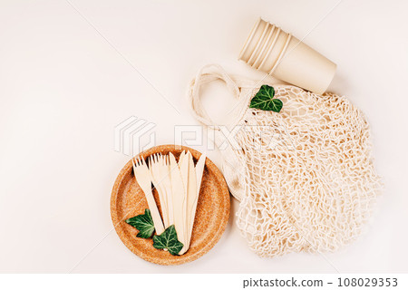 Recycling,eco-friendly concept.Disposable eco cutlery,plates,spoons,knives,forks on a light background.Fabric bag for food delivery.Eco craft paper tableware.Paper cups,fast food containers.Copy space 108029353