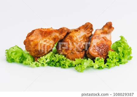 Chicken wings fried until half cooked, semi-finished product with fresh herbs on a white background. Fast food. Quick cooking at home. Copy space.Fast cooking.Fast homemade food. 108029387