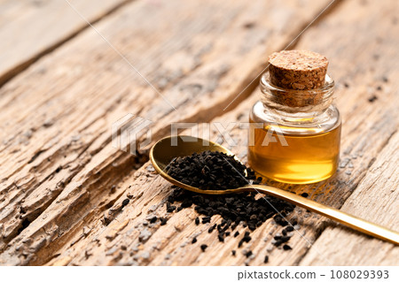 Black cumin oil and seeds on wooden background with copy space Black cumin oil and seeds on wooden background with copy space 108029393
