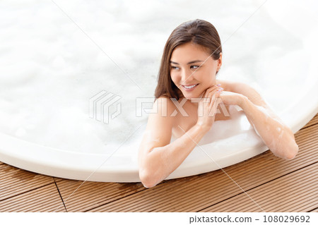 Beautiful Asian girl taking bubble bath. Comfortable house or apartment, interior design, resort and spa. 108029692