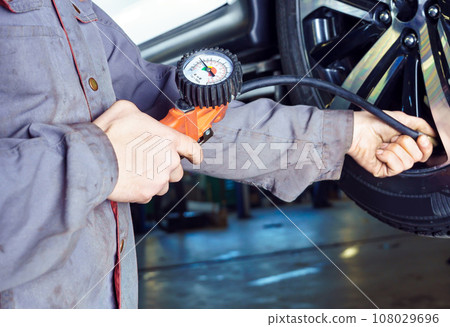 Tire change and inflation, car service and vehicle repair. Mechanic elevators car on hoist in service station. 108029696