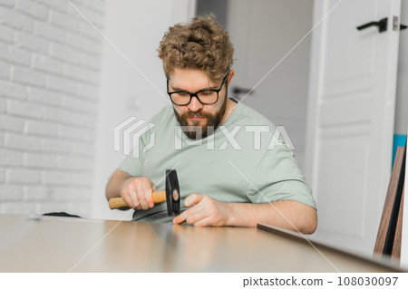 Young attractive man assembles furniture - handwerker and interior objects concept 108030097