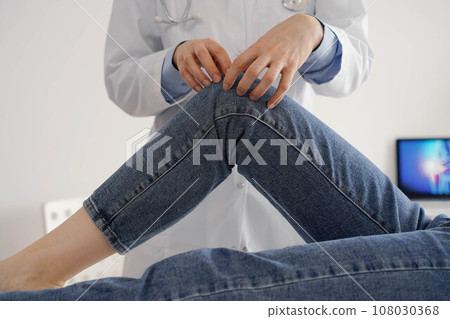 Doctor and patient are at the usual medical inspection in the clinic. Therapist examines a young woman's knee. Medicine concept Doctor and patient are at the usual medical inspection in the clinic. Therapist examines a young woman's knee. Medicine concept 108030368