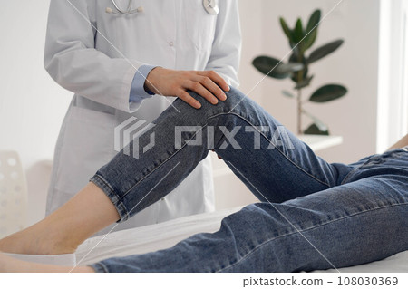 Doctor and patient are at the usual medical inspection in the clinic. Therapist examines a young woman's knee. Medicine concept Doctor and patient are at the usual medical inspection in the clinic. Therapist examines a young woman's knee. Medicine concept 108030369