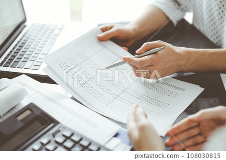 Female accountant pointing with a pen into audit paper while explaining tax counting results, close up. Business audit and finance concepts 108030815