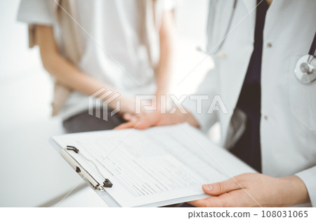 Doctor and child patient. The physician is holding clipboard with medication history records form near a boy. The concept of ideal health in medicine 108031065