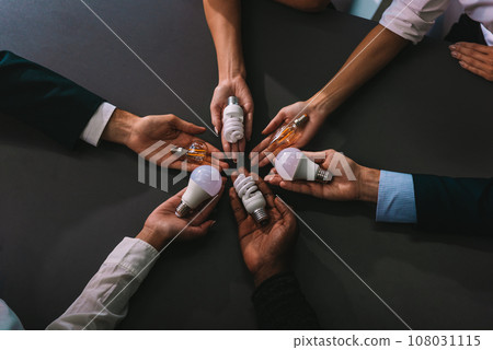 Teamwork and brainstorming concept with businessmen that share an idea with a lamp Teamwork and brainstorming concept with businessmen that share an idea with a lamp 108031115