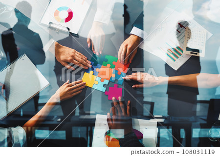 Businessmen working together to build a puzzle as teamwork, partnership and integration concept Businessmen working together to build a puzzle as teamwork, partnership and integration concept 108031119