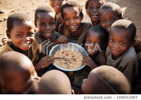 Group of African children eat meager food with their hands from a large metal plate Group of African children eat meager food with their hands from a large metal plate 108032065