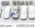 Winter parking lot cars under snow covered cars snow clearing. Parked cars snow removal. Cover winter yard above view top. Courtyard. Winter season. Cold weather conditions. Snowbound. Frosty morning 108032549