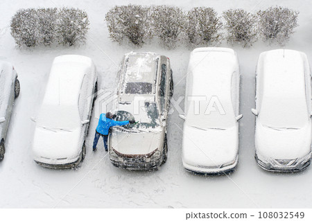 Winter parking lot cars under snow covered cars snow clearing. Parked cars snow removal. Cover winter yard above view top. Courtyard. Winter season. Cold weather conditions. Snowbound. Frosty morning 108032549