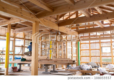A craftsman is plastering the base of a mud wall at a construction site for a wooden house. 108033557