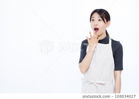A housewife in her 30s smiling and surprised in front of a white background 108034027