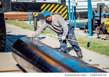 Laying metal pipes for natural gas transportation. Construction of gas pipeline. Worker paints metal Laying metal pipes for natural gas transportation. Construction of gas pipeline. Worker paints metal 108034238
