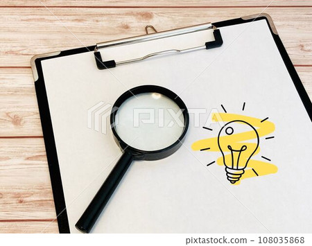 binder, magnifying glass and miniature light bulb 108035868