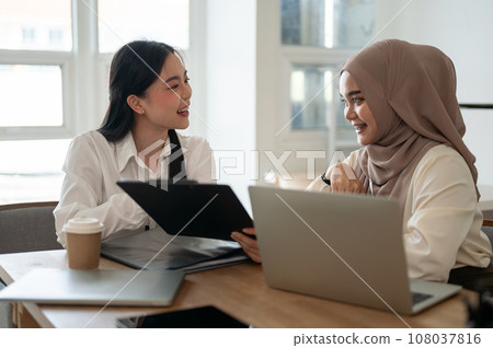 An attractive Asian businesswoman and a beautiful Asian-Muslim businesswoman are working together. An attractive Asian businesswoman and a beautiful Asian-Muslim businesswoman are working together. 108037816