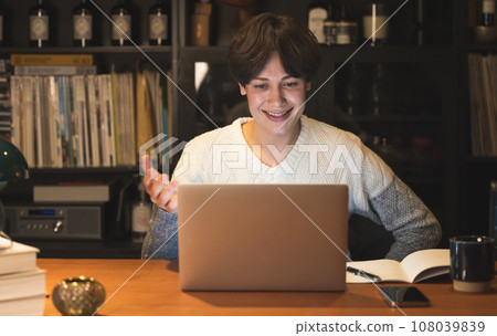 A man having a video conference at home at night A man having a video conference at home at night 108039839