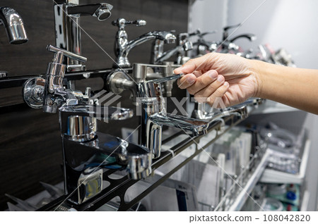 Male hand choosing water tap in home design store 108042820