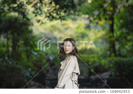 一個穿著風衣的女人站在森林公園裡 108042953