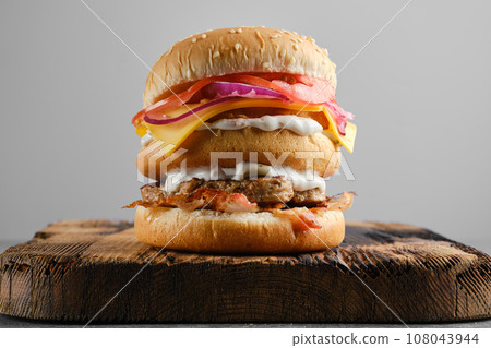 Monster double burger on wooden board, front view 108043944