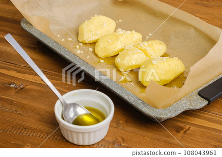 Sliced potato on a parchment in baking tray 108043961