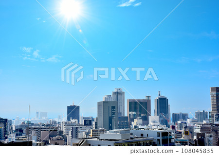 Sunlight shining in the blue sky and cityscape with skyscrapers, condominiums, and office buildings lined up. Sunlight shining in the blue sky and cityscape with skyscrapers, condominiums, and office buildings lined up. 108045835