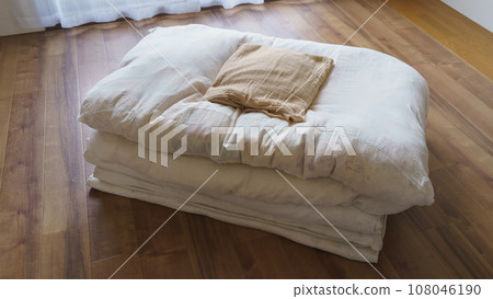 Futon and pillows folded on the flooring 108046190
