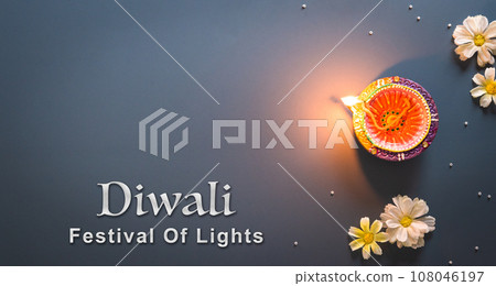 Happy Diwali - Clay Diya lamps lit during Diwali, Hindu festival of lights celebration. Colorful traditional oil lamp diya on blue background 108046197