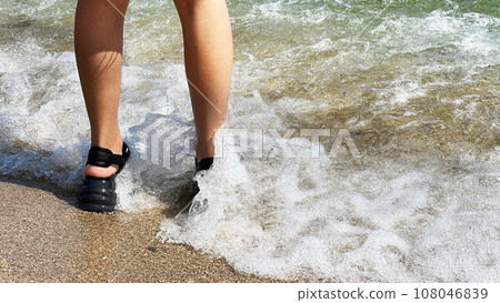 Woman's feet playing in the water on a tropical beach 108046839