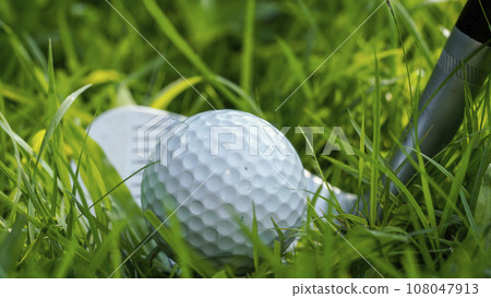 Golf club and golf ball close up in grass field with sunset. 108047913