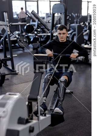 tired sweaty man training with rowing machine at gym 108050019