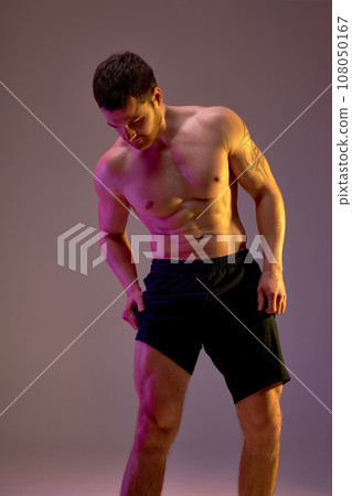 strong sportsman looking at his biceps on legs strong sportsman looking at his biceps on legs 108050167