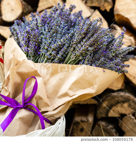 A lush and large bouquet of lavender wrapped in paper on a background of firewood 108050178