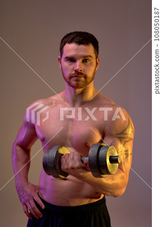 bearded young sweaty man holding dumbbell looking at camera bearded young sweaty man holding dumbbell looking at camera 108050187