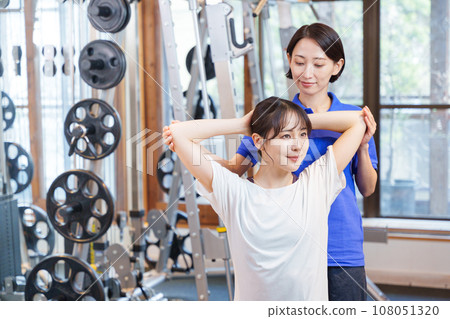 Woman receiving personal stretching at the gym Woman receiving personal stretching at the gym 108051320