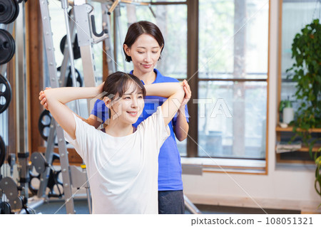 Woman receiving personal stretching at the gym Woman receiving personal stretching at the gym 108051321