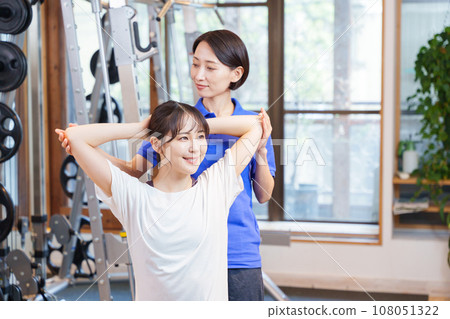 Woman receiving personal stretching at the gym 108051322