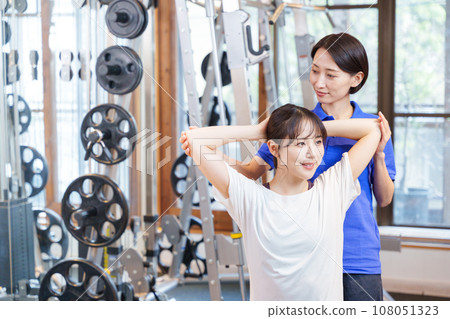 Woman receiving personal stretching at the gym Woman receiving personal stretching at the gym 108051323
