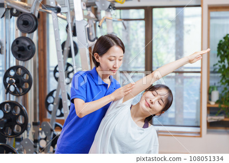 Woman receiving personal stretching at the gym Woman receiving personal stretching at the gym 108051334