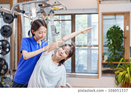Woman receiving personal stretching at the gym Woman receiving personal stretching at the gym 108051337