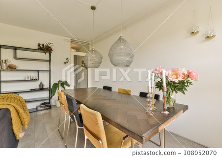 a dining room with flowers in vases on the table next to the couch and shelves for storage behind it a dining room with flowers in vases on the table next to the couch and shelves for storage behind it 108052070