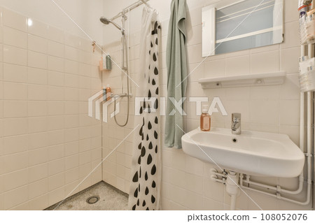 a bathroom with black and white tiles on the walls, sink, mirror, and shower stall in it's corner a bathroom with black and white tiles on the walls, sink, mirror, and shower stall in it's corner 108052076