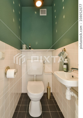 a bathroom with green walls and white tiles on the floor, along with a toilet in the corner of the room a bathroom with green walls and white tiles on the floor, along with a toilet in the corner of the room 108052077