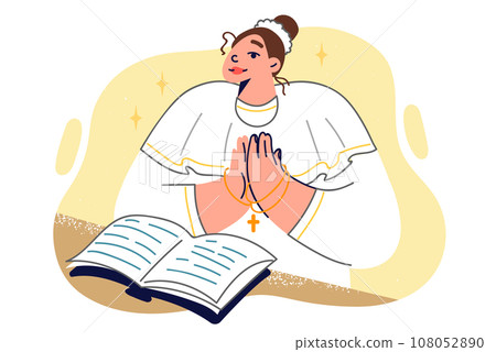 Woman nun stands near open bible and holds chain with christian cross in hands making prayer gesture Woman nun stands near open bible and holds chain with christian cross in hands making prayer gesture 108052890