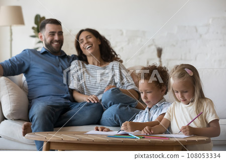 Cheerful young parents resting on couch at cozy home Cheerful young parents resting on couch at cozy home 108053334